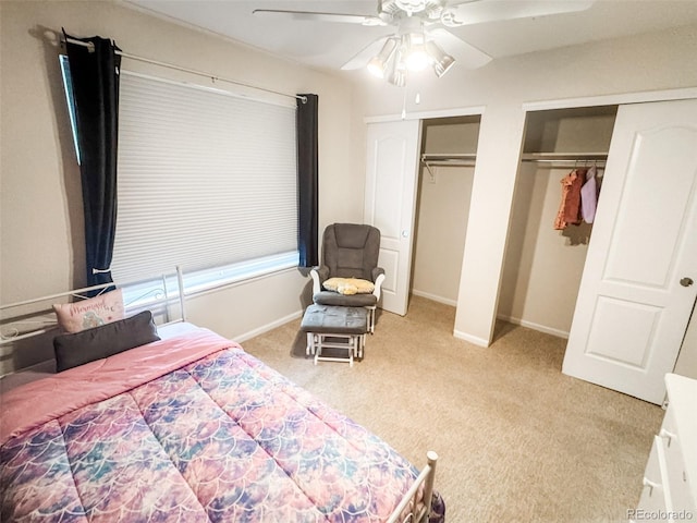 bedroom with ceiling fan, light colored carpet, multiple closets, and baseboards