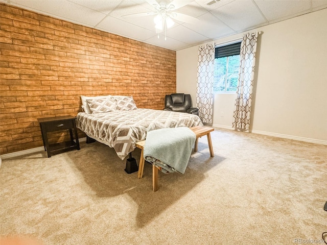 bedroom with a ceiling fan, carpet floors, brick wall, a paneled ceiling, and baseboards