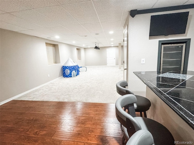 playroom featuring hardwood / wood-style floors, recessed lighting, baseboards, carpet floors, and a paneled ceiling