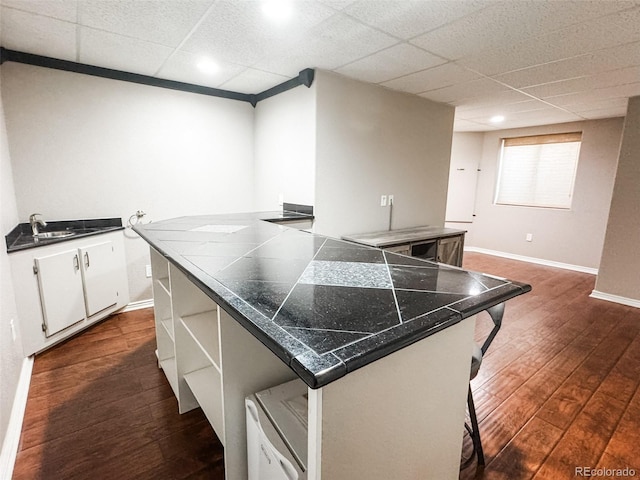 kitchen with dark wood-style floors, white cabinetry, open shelves, a drop ceiling, and a kitchen bar