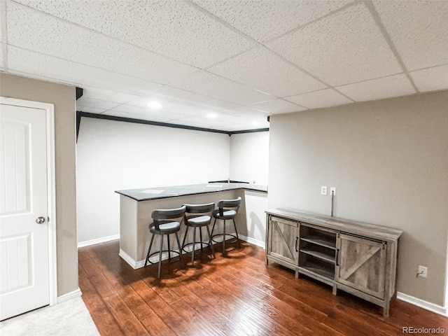 bar with dark wood finished floors, baseboards, and a drop ceiling