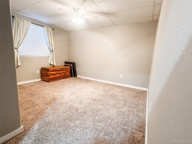 unfurnished room with carpet flooring, a paneled ceiling, baseboards, and ceiling fan