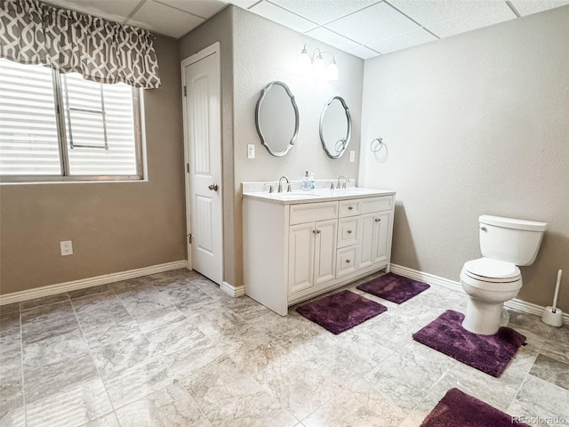 full bath featuring double vanity, a paneled ceiling, and a sink