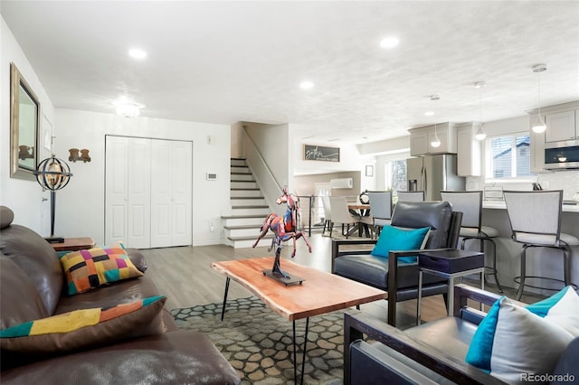 living area with recessed lighting, stairs, and wood finished floors