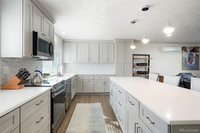 kitchen with a wall mounted AC, backsplash, a center island, stainless steel appliances, and light wood-style floors