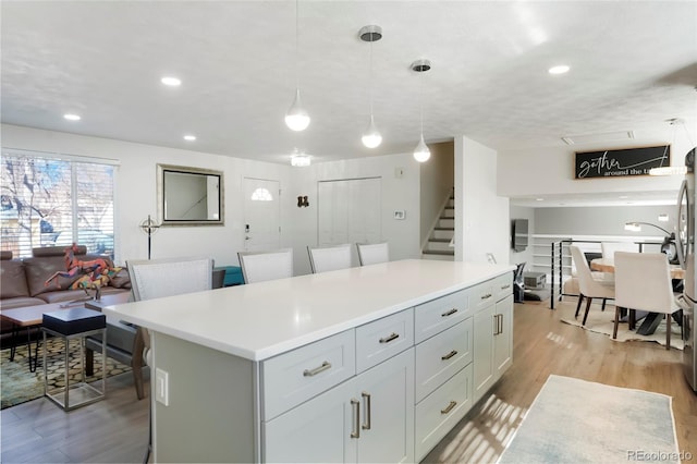 kitchen with light wood-type flooring, a kitchen island, open floor plan, and light countertops