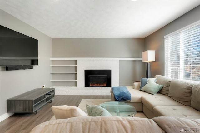 living room with a fireplace, baseboards, and wood finished floors