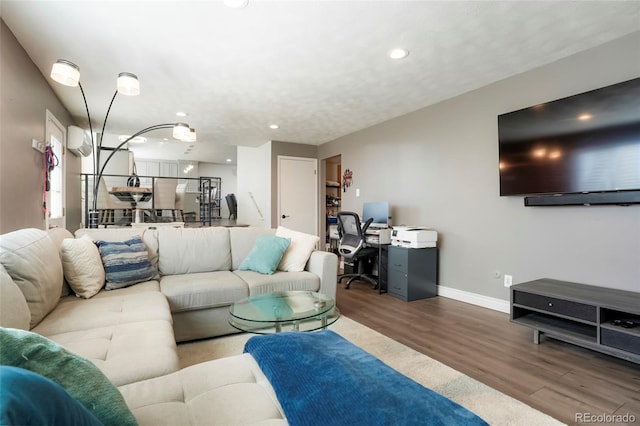 living area featuring recessed lighting, wood finished floors, baseboards, and a wall mounted air conditioner