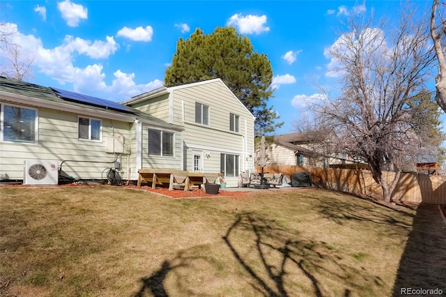 back of house featuring a yard, a patio, solar panels, and fence