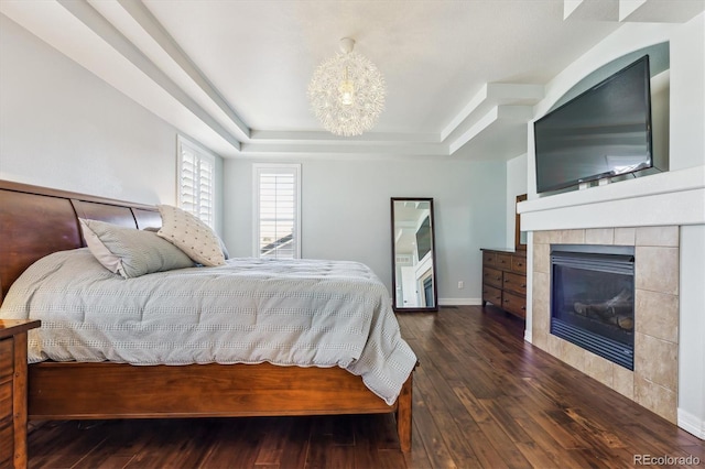6927 Winter Ridge Pl, Castle Pines, CO 80108 - bedroom with a tile fireplace, wood-type flooring, a notable chandelier, and a tray ceiling