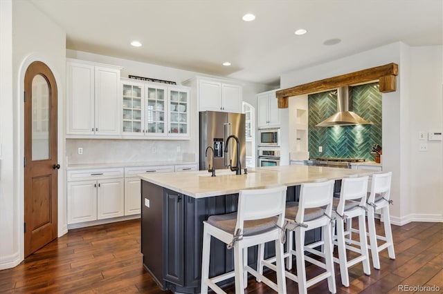 6927 Winter Ridge Pl, Castle Pines, CO 80108 - kitchen featuring dark wood-style flooring, glass insert cabinets, backsplash, wall chimney exhaust hood, and appliances with stainless steel finishes