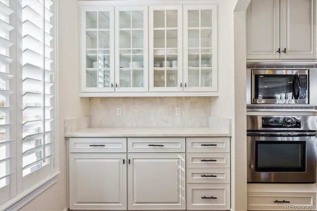 6927 Winter Ridge Pl, Castle Pines, CO 80108 - bar with arched walkways, backsplash, and appliances with stainless steel finishes