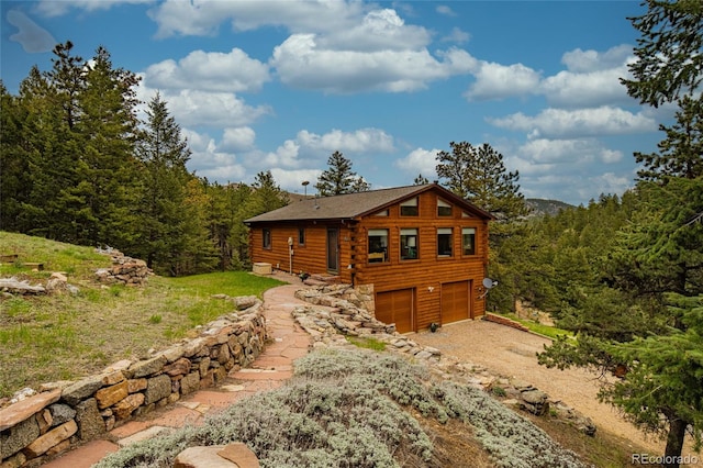 310 Wendelyn Way, Boulder, CO 80302 - rear view of property with log siding, driveway, an attached garage, and a view of trees