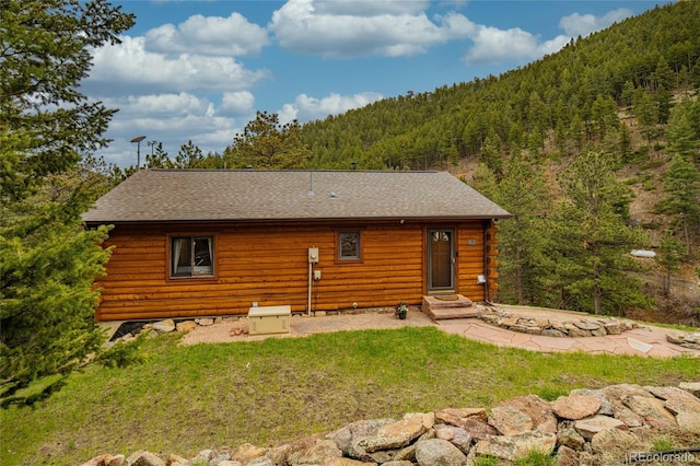310 Wendelyn Way, Boulder, CO 80302 - rear view of house featuring a forest view, log exterior, roof with shingles, and a lawn
