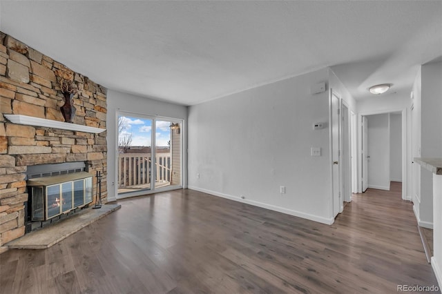 4460 S Pitkin St Unit 120, Aurora, CO 80015 - unfurnished living room featuring wood finished floors, a stone fireplace, and baseboards
