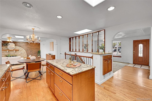 kitchen with a kitchen island, light wood-style flooring, arched walkways, and brick wall