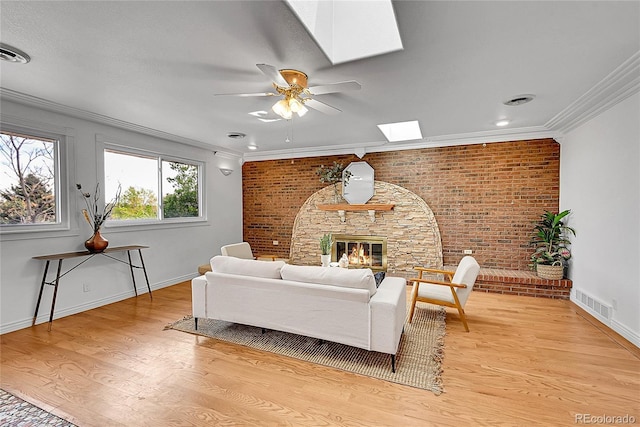 living area with a skylight, brick wall, light wood-type flooring, visible vents, and ceiling fan