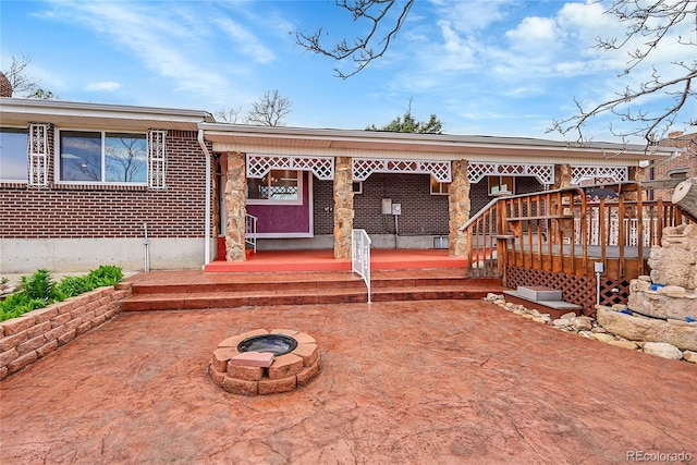 rear view of house with an outdoor fire pit, brick siding, and a patio area
