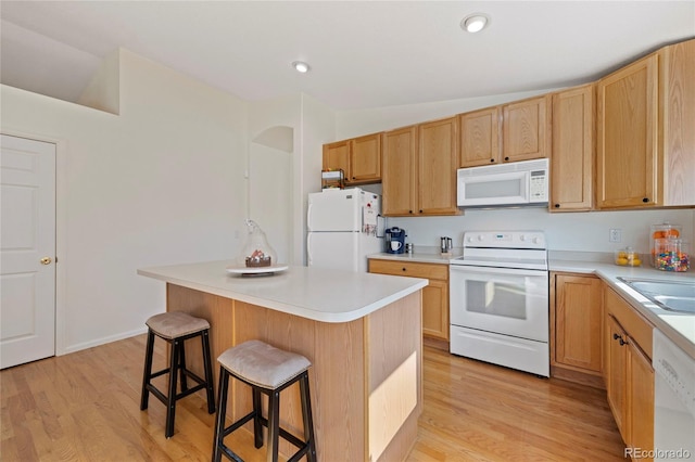 kitchen with white appliances, a kitchen breakfast bar, light countertops, and a center island