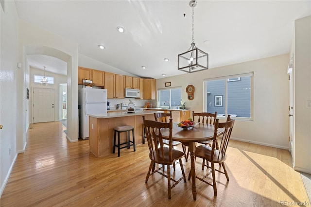 dining room with arched walkways, a notable chandelier, recessed lighting, vaulted ceiling, and light wood-type flooring