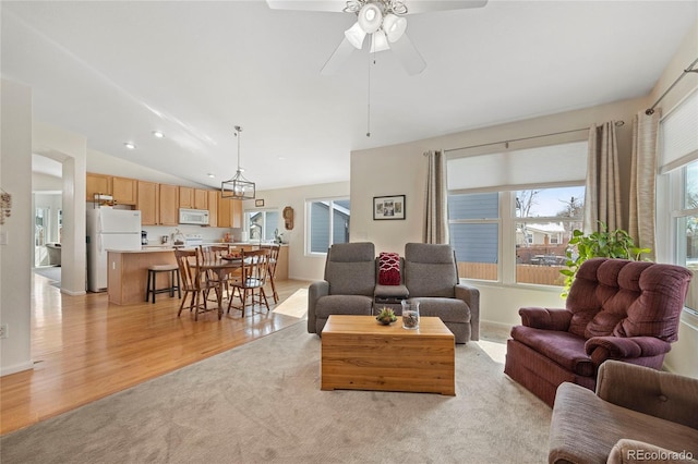 living room with lofted ceiling, light wood finished floors, and a ceiling fan