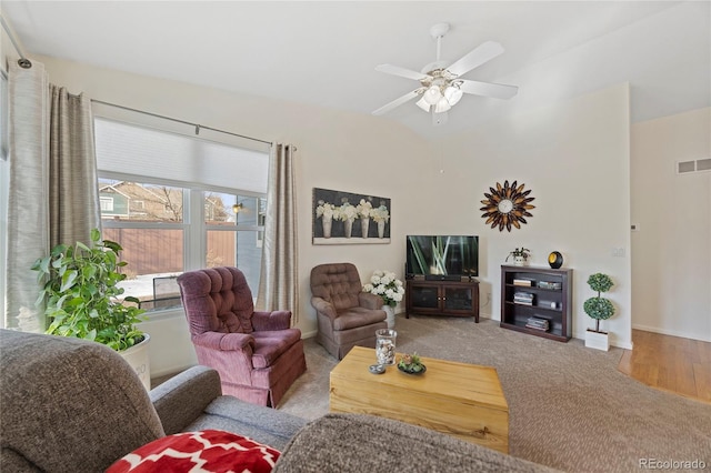 living area featuring ceiling fan, visible vents, and light colored carpet