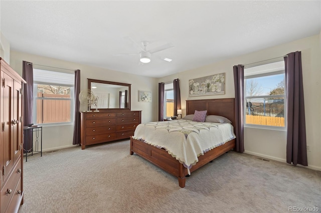 bedroom with light colored carpet, baseboards, and multiple windows