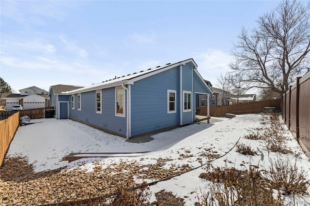 snow covered back of property featuring crawl space and a fenced backyard