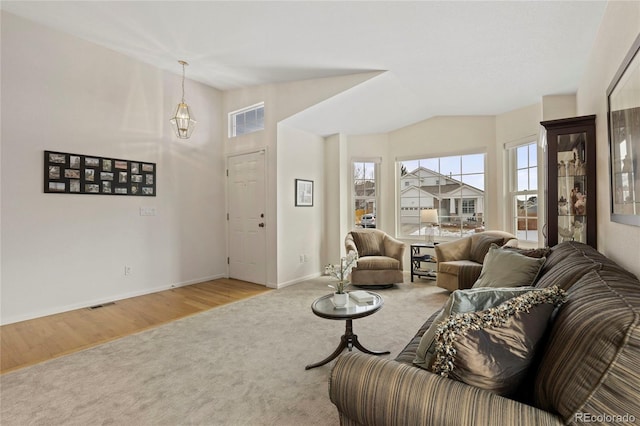 living room featuring light wood finished floors, lofted ceiling, visible vents, light carpet, and baseboards