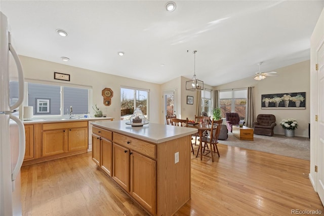 kitchen featuring open floor plan, light countertops, a wealth of natural light, a center island, and decorative light fixtures