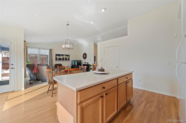 kitchen with lofted ceiling, a kitchen island, open floor plan, hanging light fixtures, and light countertops