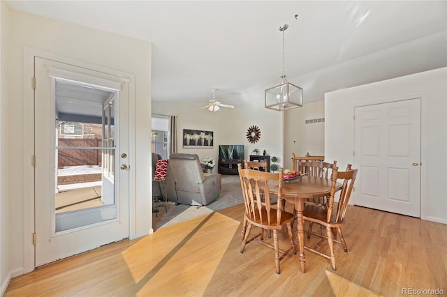 dining space with lofted ceiling, ceiling fan with notable chandelier, and light wood-style flooring