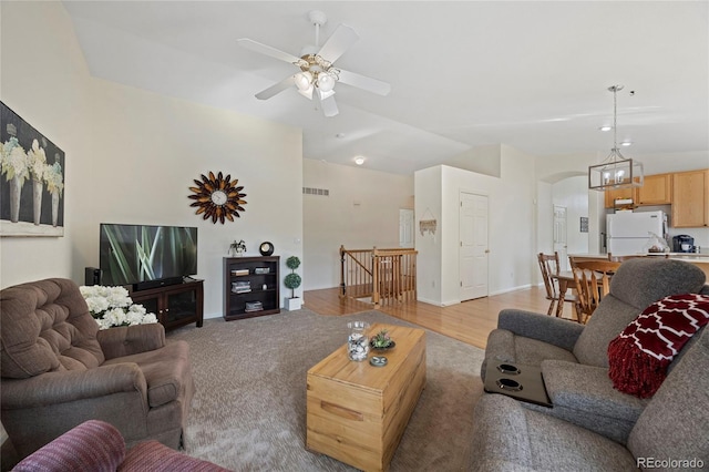 living area with arched walkways, lofted ceiling, visible vents, a ceiling fan, and light wood-type flooring