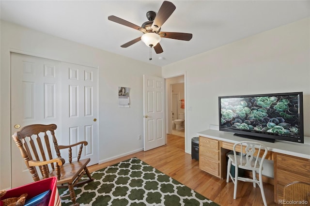 office area featuring light wood finished floors, built in study area, a ceiling fan, and baseboards