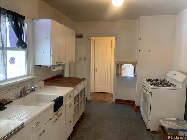 kitchen featuring sink, gas range gas stove, and white cabinets