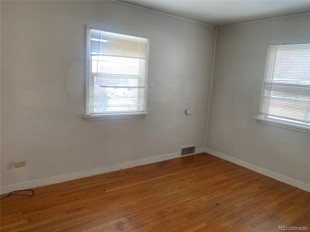 empty room with hardwood / wood-style flooring and a healthy amount of sunlight