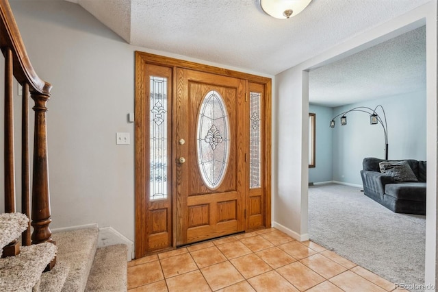 foyer with light tile patterned floors, light colored carpet, a textured ceiling, and stairs