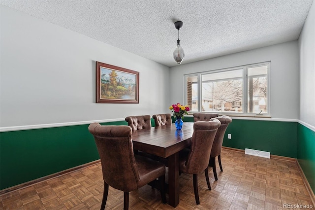 dining space with a textured ceiling, visible vents, and baseboards