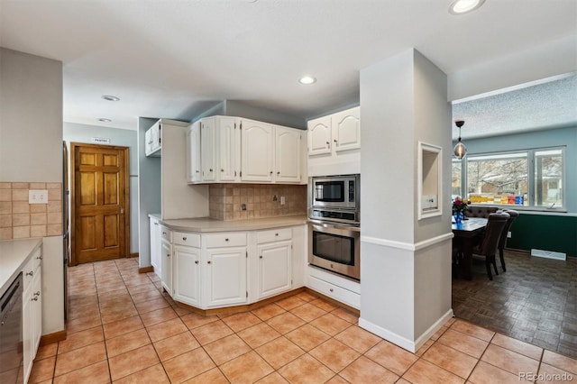 kitchen featuring light tile patterned floors, stainless steel appliances, light countertops, backsplash, and white cabinets