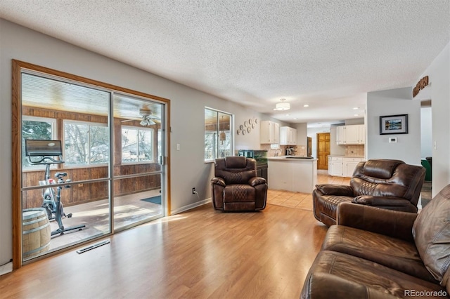 living area featuring light wood-type flooring, baseboards, visible vents, and a textured ceiling