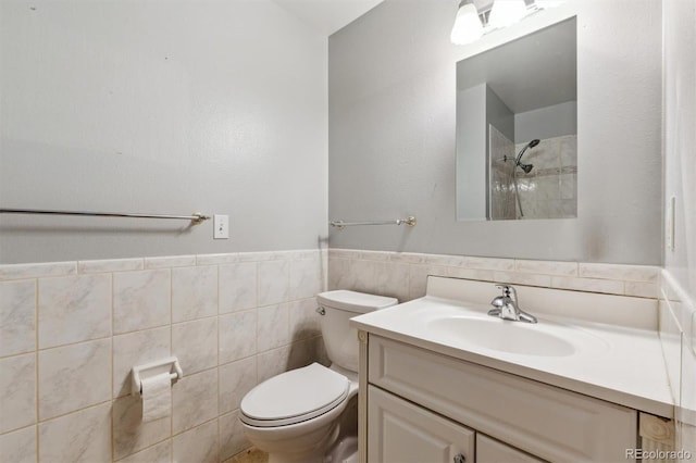 bathroom with a wainscoted wall, vanity, toilet, and tile walls