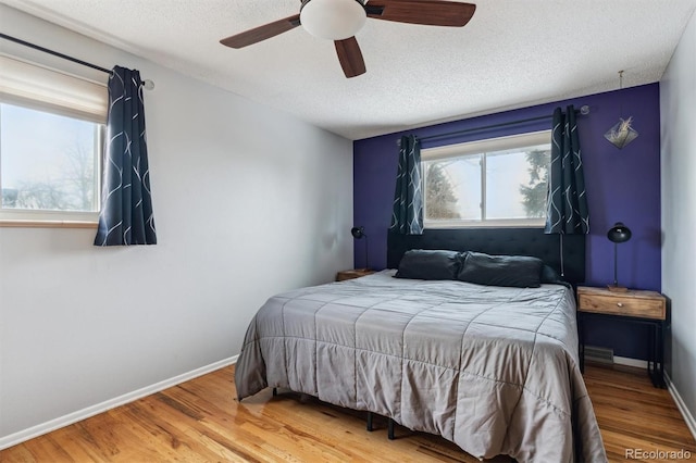 bedroom with a textured ceiling, baseboards, and wood finished floors