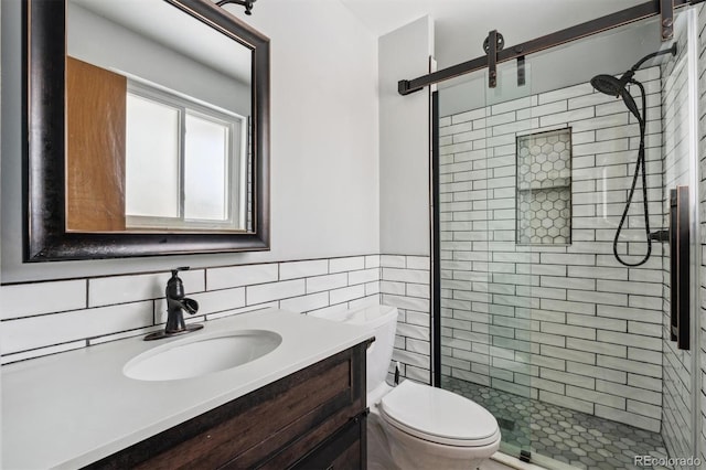 bathroom featuring a stall shower, toilet, a wainscoted wall, vanity, and tile walls