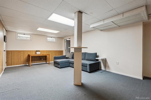 below grade area featuring carpet flooring, wainscoting, wooden walls, and a drop ceiling