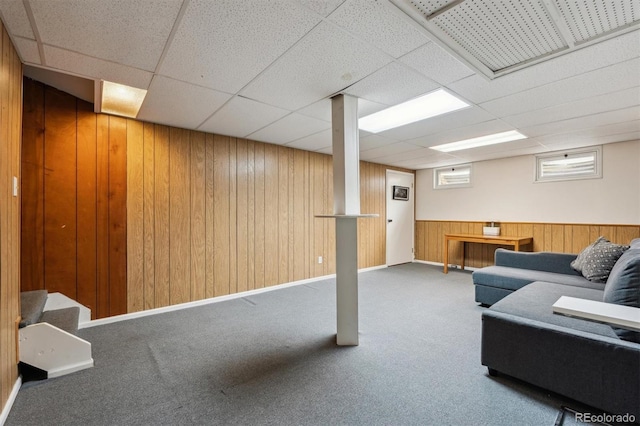 living room with wood walls, stairway, a drop ceiling, and carpet flooring