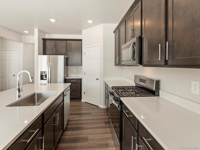 kitchen with dark brown cabinetry, dark wood-style floors, stainless steel appliances, light countertops, and a sink