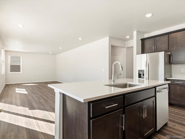 kitchen featuring a center island with sink, appliances with stainless steel finishes, open floor plan, light countertops, and a sink