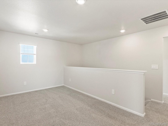 carpeted empty room featuring baseboards, visible vents, and recessed lighting