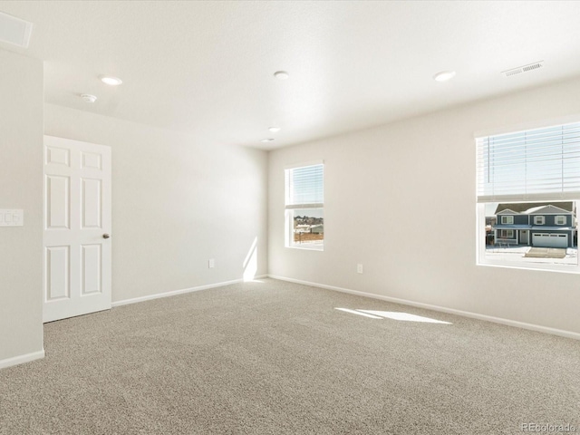 carpeted empty room featuring visible vents, baseboards, and recessed lighting