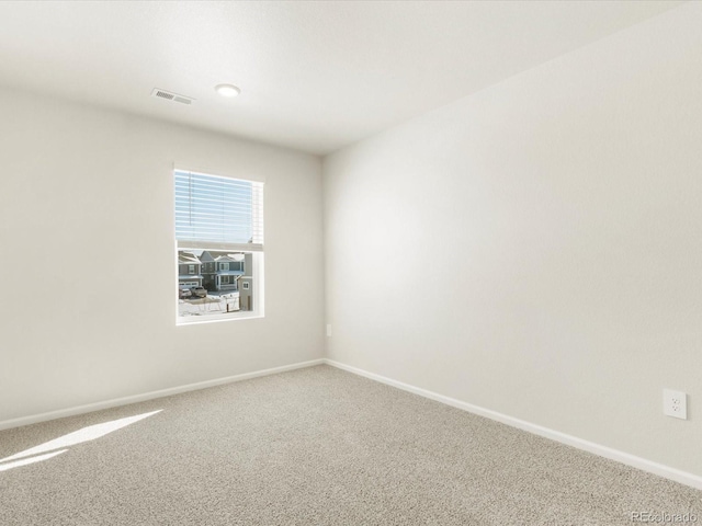 empty room featuring carpet, visible vents, and baseboards